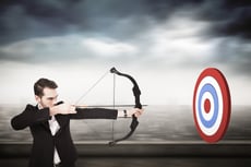 Elegant businessman shooting bow and arrow against cityscape