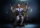 Joyful businessman sitting on chair under money rain